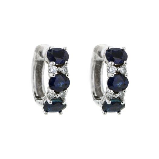 white gold hoop earrings featuring three oval-cut blue sapphires with two mini white diamond rounds set in between