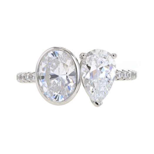 white gold band lined with diamonds featuring two center stones one oval one pear