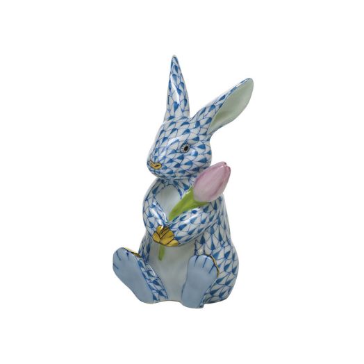 seated blue bunny with golden accents holding a pink tulip 